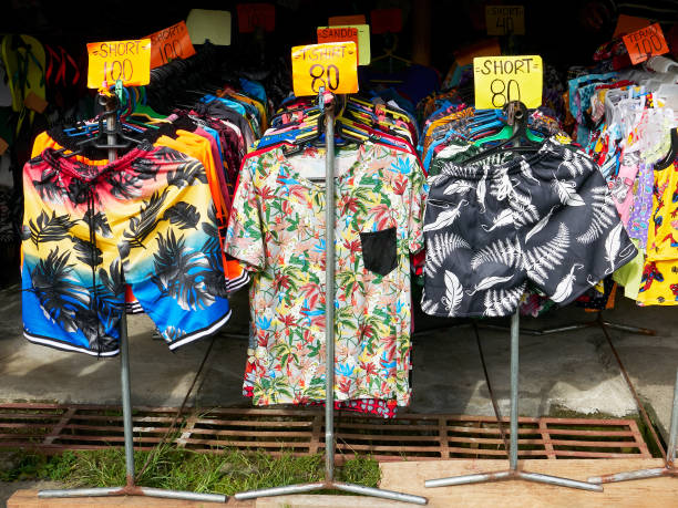 Shop selling colorful shorts and t-shirts in Asia Several display stands with hangers full of colorful clothes for sale in a stall in the Philippines, a common sight during the covid pandemic times divisoria market stock pictures, royalty-free photos & images