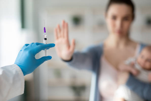 Vaccine Hesitancy. Woman With Newborn Baby Refusing Syringe In Doctor's Hand Vaccine Hesitancy. Woman With Newborn Baby Refusing Syringe In Doctor's Hand, Showing Stop Gesture With Open Palm, Rejecting Injection For Her And Infant Child, Selective Focus, Closeup refusing stock pictures, royalty-free photos & images