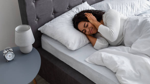 istock Stressed black woman covering ears lying in bed 1317937635