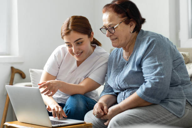 istock Old woman with nurse using laptop at home 1317938148