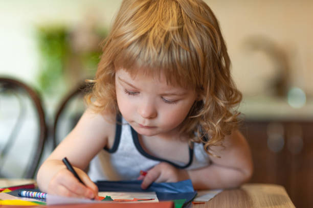 istock little curly boy draws with a colored pencil home 1317941872