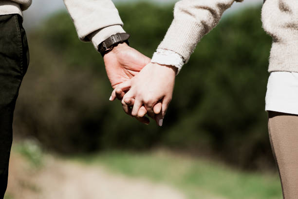 istock Couple hold hands in green field on sunset 1317943004