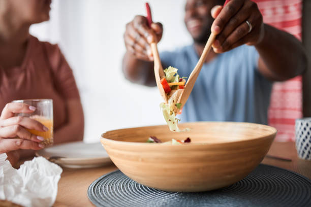 istock Man mixing salad with wooden spoons while preparing dinner 1317944487