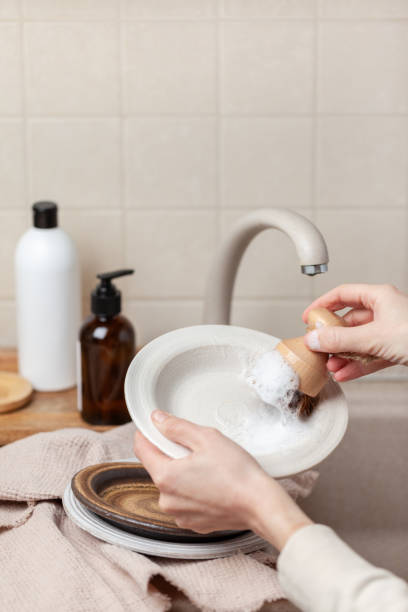 женщина мыть посуду на кухне - sustainable resources water conservation water faucet стоковые фото и изображения