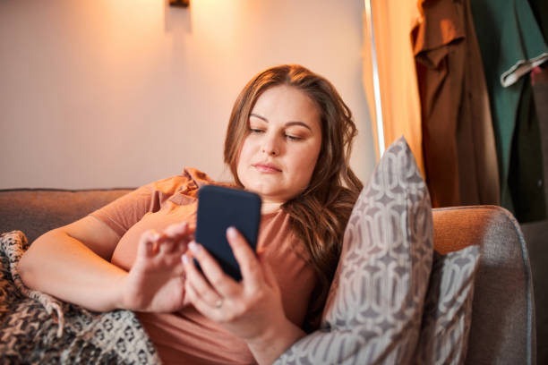 istock Woman using her smartphone while laying at the sofa near her husband 1317944711