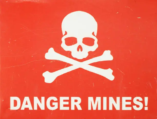 Jolly Roger (white skull-and-crossbones) on a red sign warning of the danger of landmines