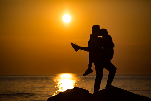 Young Couple Kissing on Rocky Coastline During Sunset.