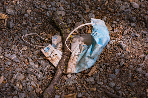 A medical mask is thrown away in a meadow and pollutes the environment