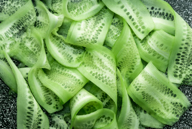 food background. sliced thin slices of fresh green cucumber. on a dark background, a rich green color. top view, macro