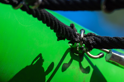 The black synthetic rope is frayed at the attachment point and will soon break. Danger. Children's playground. Risk.