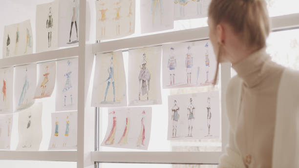 istock Female fashion designer at work. Creating new collection, picking projects hanging on a window 1317952910