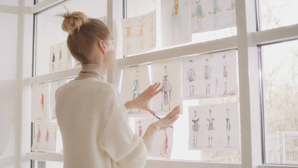 istock Female fashion designer at work. Creating new collection, picking projects hanging on a window 1317952929