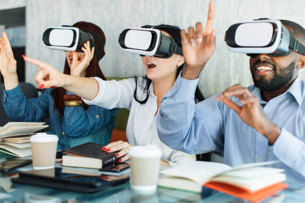 istock Old and new technologies, traditional and digital. Excited young creative three multiethnic friends sitting in VR headsets while laughing and spending time in modern cafe. 1317955949