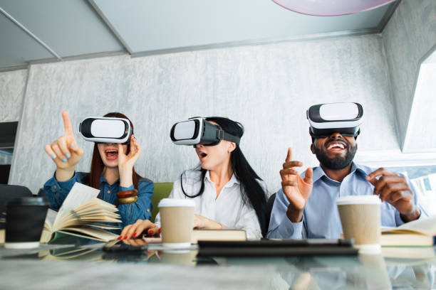 istock Advanced digital 3d virtual reality technology. Cheerful surprised three multiracial friends sitting in cafe with open mouth and wearing VR headsets, trying a new video game or study project. 1317955955
