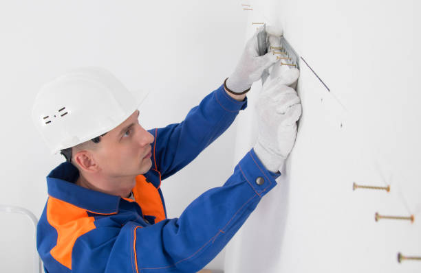 istock a worker in a protective helmet, on a white wall, sets a bar for fixing hanging cabinets of kitchen furniture, close-up 1317956909