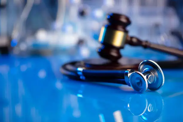 Gavel and stethoscope on the glass table. Blue light.