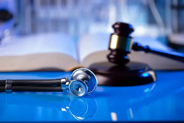 Gavel and stethoscope on the glass table. Blue light.