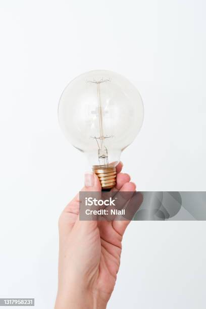 Woman Holding Lamp Presenting New Ideas For Project Man Hand Showing Bulb And New Technologies Hand Holding Lighbulb Displaying New Idea Stock Photo - Download Image Now