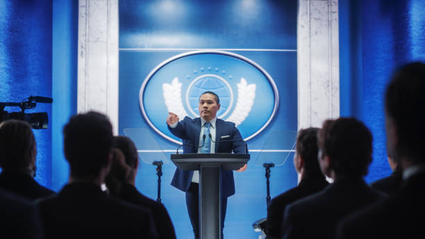 istock Organization Chinese Representative Speaking at Press Conference in Government Building. Press Officer Delivering a Speech at Summit Meeting. Minister Speaking at Congress Hearing. 1317961739