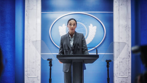 istock Organization Female Representative Speaking at a Press Conference in Government Building. Press Office Representative Delivering a Speech at a Summit. Minister Speaking to a Congress Hearing. 1317961776