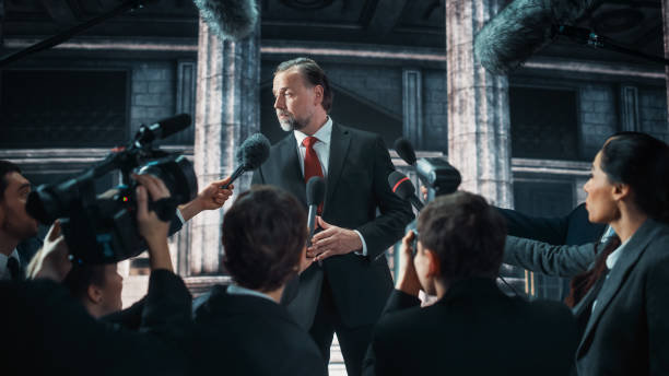 istock Organization Representative Answering Press Questions and Giving Interview Outside a Parliament, Court or Other Government Building. Press Officer or Businessman Crowded by News Journalists. 1317961799