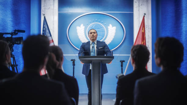 istock Chinese Organization Representative Speaking at Press Conference. Minister Delivering a Speech at Congress Hearing. Backdrop with United States of America and People's Republic of China Flags. 1317961827