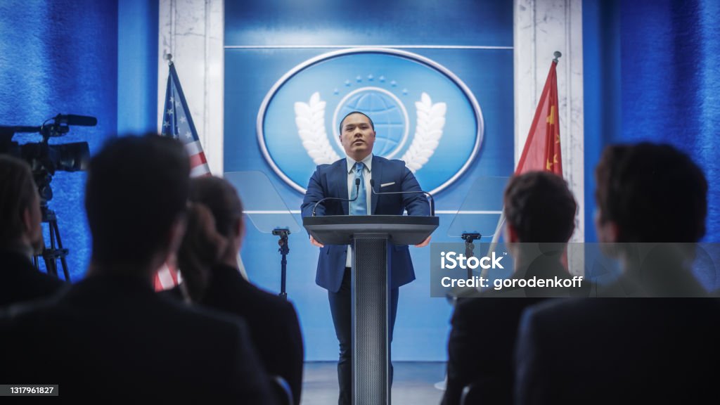 Chinese Organization Representative Speaking at Press Conference. Minister Delivering a Speech at Congress Hearing. Backdrop with United States of America and People's Republic of China Flags. Ambassador Stock Photo