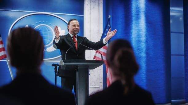 istock Charismatic Organization Representative Greeting Supporters at Conference in USA Government Building. Press Office Representative Delivering a Speech at a Summit. Minister Speaking to Congress. 1317961895