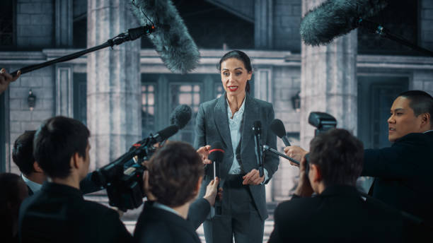 istock Organization Representative Answering Press Questions and Giving Interview Outside a Parliament, Court or Other Government Building. Press Officer or Businesswoman Crowded by News Journalists. 1317961930