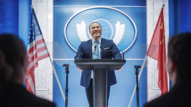istock Chinese Organization Representative Speaking at Press Conference. Minister Delivering a Speech at Congress Hearing. Backdrop with United States of America and People's Republic of China Flags. 1317961933