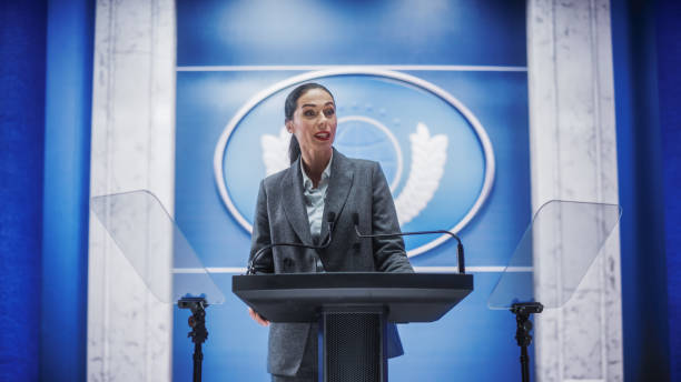 istock Organization Female Representative Speaking at a Press Conference in Government Building. Press Office Representative Delivering a Speech at a Summit. Minister Speaking to a Congress Hearing. 1317961951