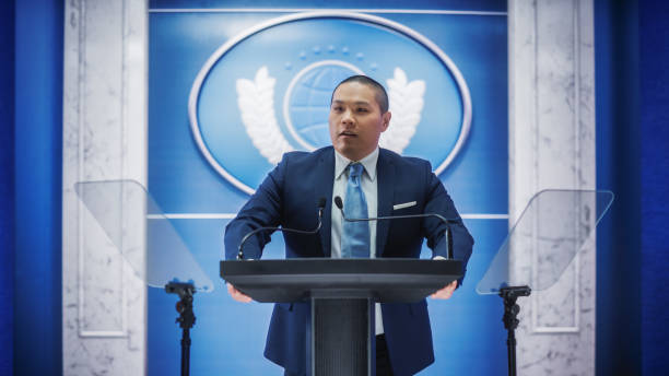 istock Organization Chinese Representative Speaking at Press Conference in Government Building. Press Officer Delivering a Speech at Summit Meeting. Minister Speaking at Congress Hearing. 1317961955