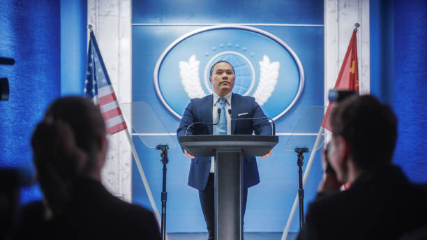istock Chinese Organization Representative Speaking at Press Conference. Minister Delivering a Speech at Congress Hearing. Backdrop with United States of America and People's Republic of China Flags. 1317961974