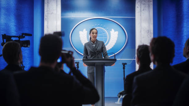 Organization Female Representative Speaking at a Press Conference in Government Building. Press Office Representative Delivering a Speech at a Summit. Minister Speaking to a Congress Hearing. representante femenina de la organización hablando en una conferencia de prensa en la construcción del gobierno. representante de la oficina de prensa pronunciando un discurso en una cumbre. ministro hablando en una audiencia en el congreso.