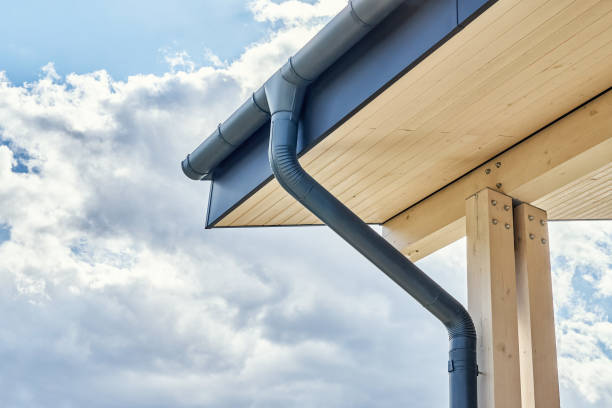 Rainwater downpipe installed on building roof with terrace Contemporary grey metal rainwater downpipe installed on roof of new building with wooden terrace on cloudy day close view eaves stock pictures, royalty-free photos & images