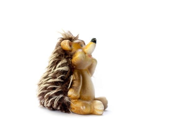 istock Isolated ceramic toy for children pensive hedgehog sitting side view on white background space for text. 1317966604