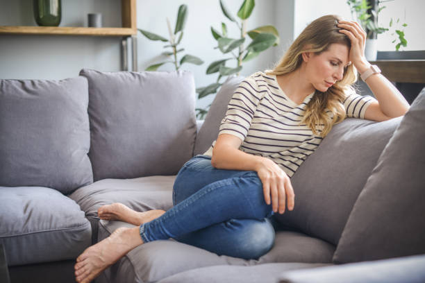 istock attractive middle aged woman sitting on the couch (negative emotions) 1317967039