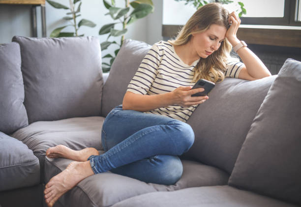 istock attractive middle aged woman sitting on the couch ( mobile phone,negative emotions) 1317967772