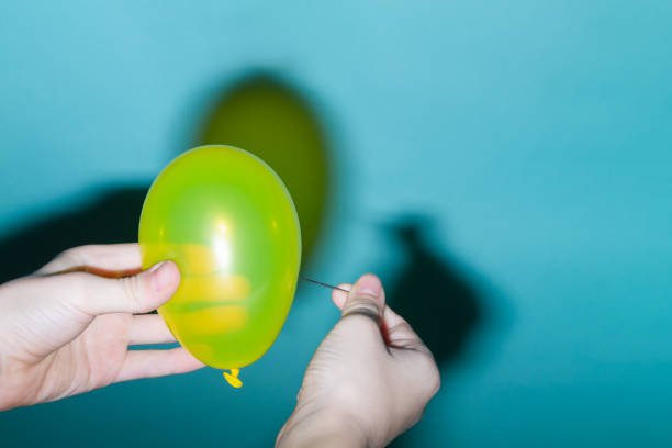 istock A man bursts a yellow balloon with a sharp needle 1317972250