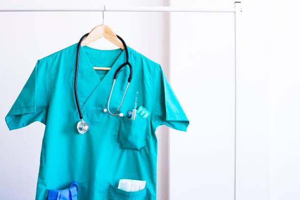 Closeup of a doctor's scrubs with stethoscope and lab coat on hangers. stock photo