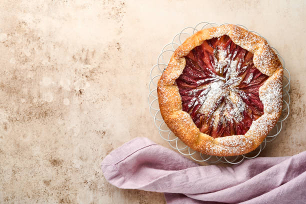 istock Homemade rhubarb galette made with star pattern on old concrete table background. Process of baking. Open pie. Christmas and New Years baked goods. Top view of homemade pie crust on the table. 1317975418