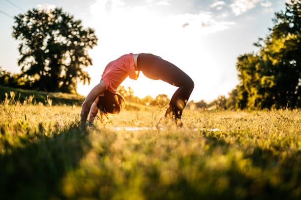 Pretty woman doing bridge position in outdoor park setting at sunset or sunrise.