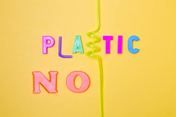 istock inscription from plastic letters and waste - no plastic, instead of letters a bottle from a bottle and cocktail tubes, yellow background, copy space, top view 1317985503