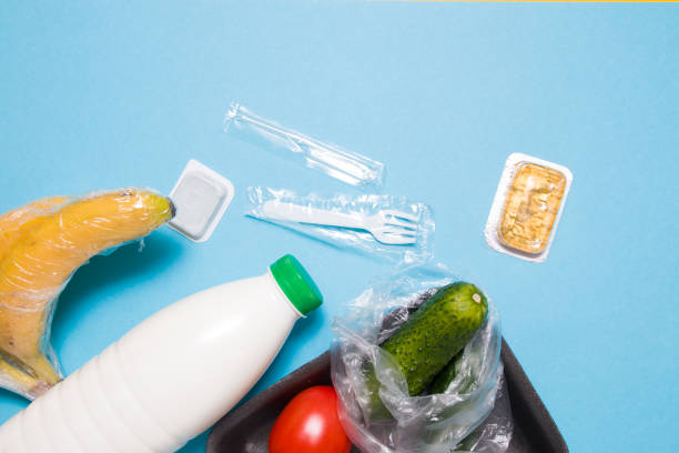istock various plastic packaging on a blue background, a tray with tomatoes and cucumbers, bananas wrapped in a film and a bottle of milk, disposable tableware, sauce and honey in a small container 1317985510