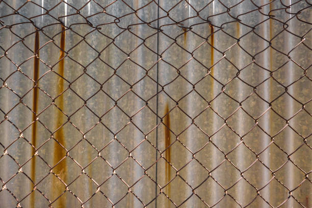 istock High metal corrugated wall with barbed wire 1317985571
