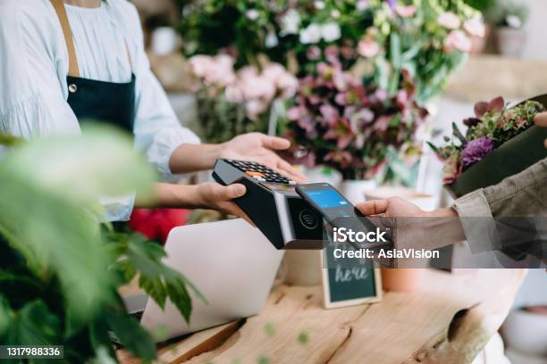 Cropped Shot Of Young Asian Man Shopping At The Flower Shop He Is Paying For A Bouquet With His Smartphone Scan And Pay A Bill On A Card Machine Making A Quick And Easy Contactless Payment Nfc Technology Tap And Go Concept Stock Photo - Download Image Now