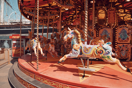 Happy positive preschool girl having a ride on the old vintage merry-go-round in city of St Malo France. Smiling child on a horse