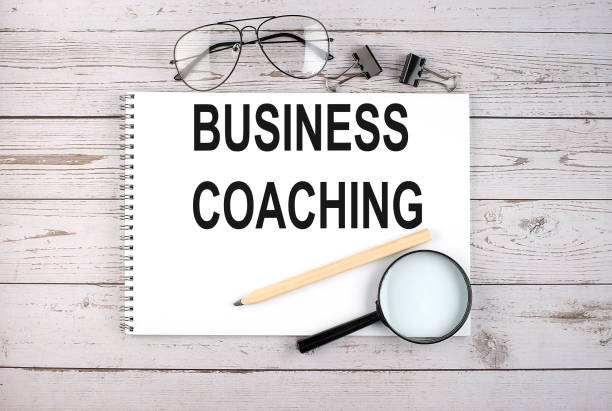 istock Notebook with text BUSINESS COACHING on the wooden table with pen, magnifier and glasses 1317997022