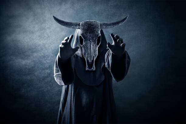 Creepy figure with animal horned skull with hands up in the dark Creepy figure with animal horned skull with hands up in the dark satan goat stock pictures, royalty-free photos & images