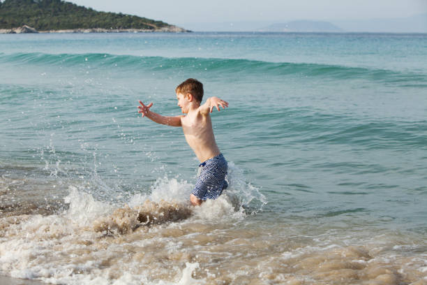 istock Little boy playing and splashing in sea waves 1317997293